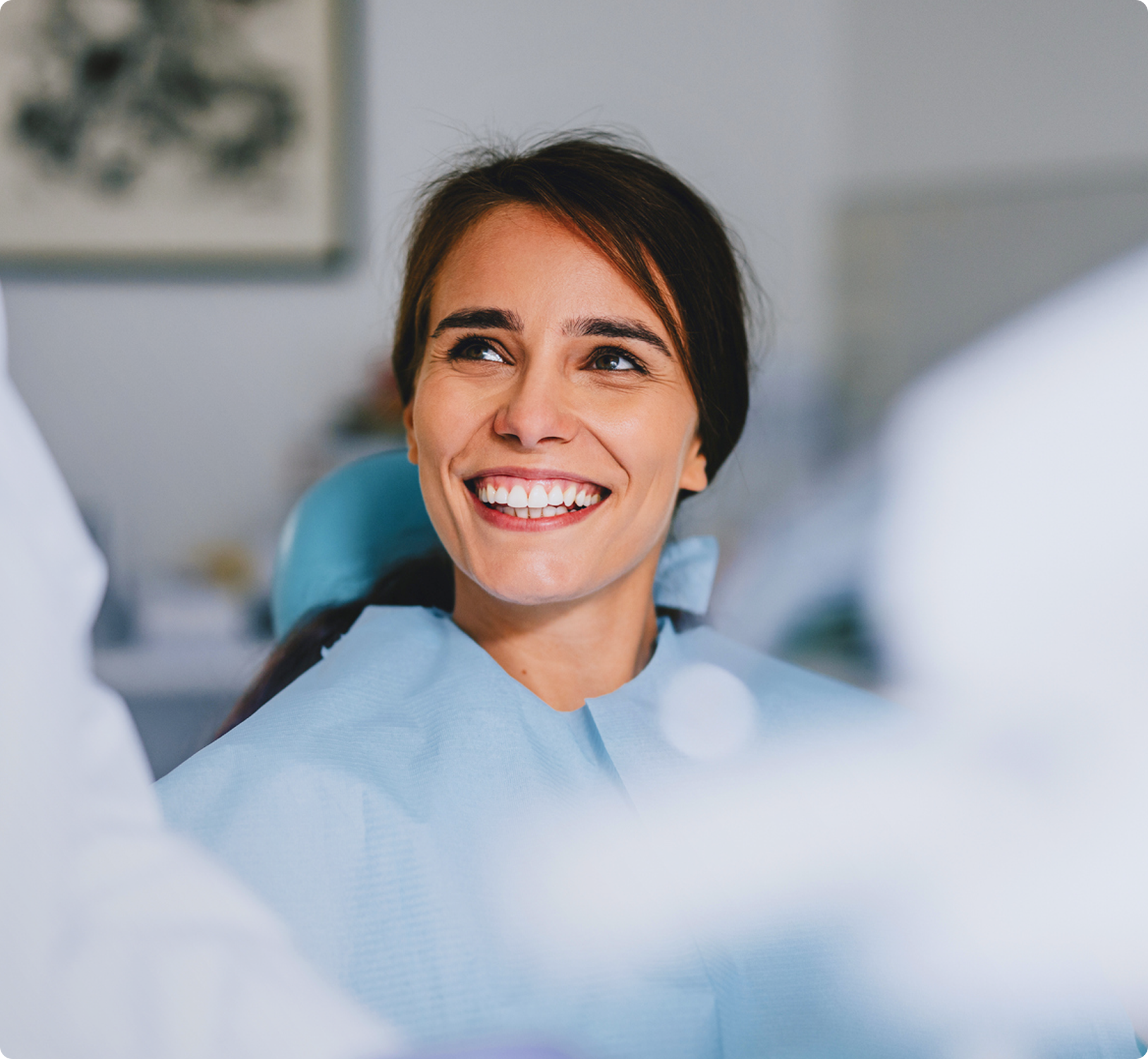 Smiling female patient sitting in a dental chair during a dental appointment, showing confidence and satisfaction with her oral health care.