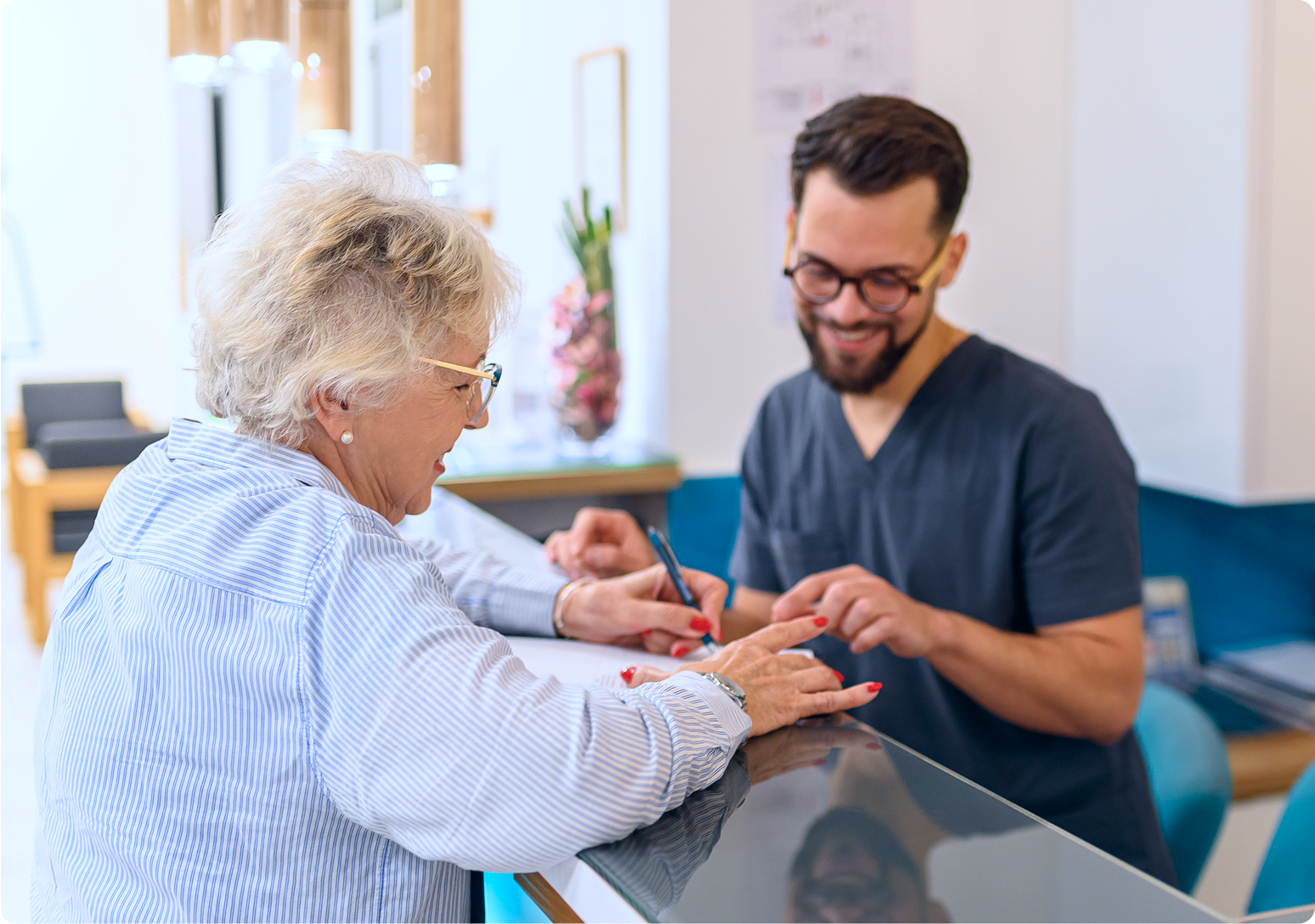 A healthcare professional assists an older adult with hand rehabilitation exercises during a therapy session.
