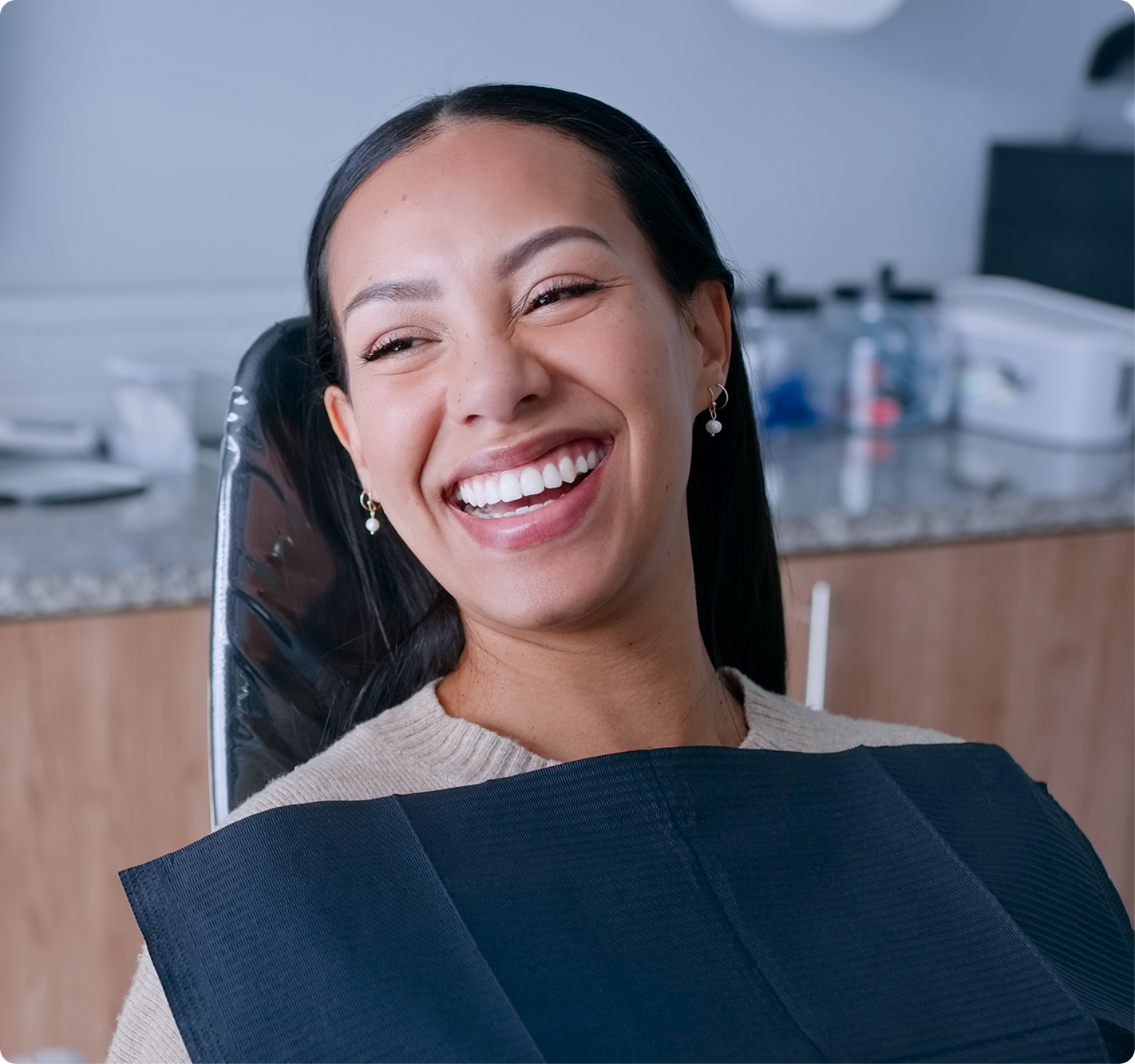 Smiling female patient sitting in a dental chair during a routine dental appointment, showing comfort and confidence after receiving professional dental care.