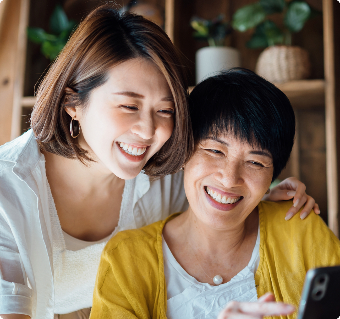 Two people smile while looking at a smartphone together, representing easy access to dental information or online patient services.