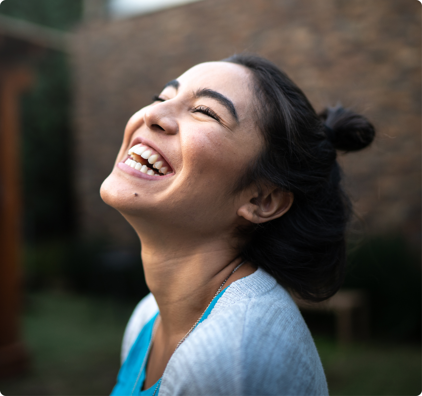 A woman smiles outdoors, representing confidence, comfort, and positive oral health.